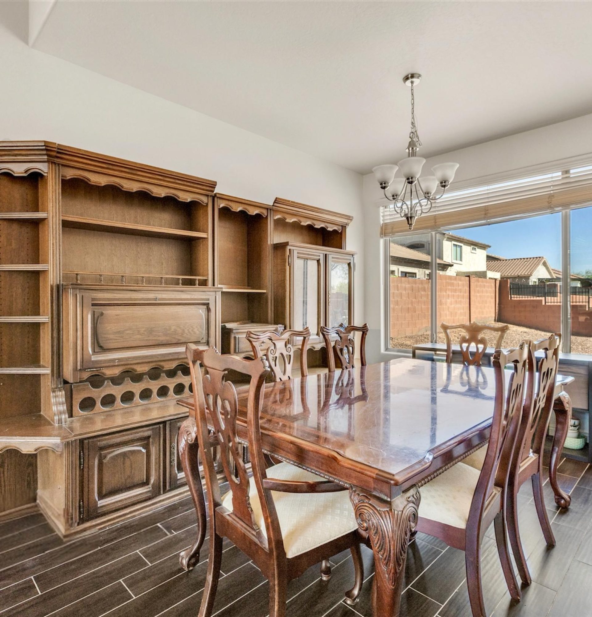Formal dining room at 845 S Cerise in Mesa, AZ, featuring a large wooden dining set, a classic hutch and buffet and a large window overlooking the private backyard in the gated La Fortina community.