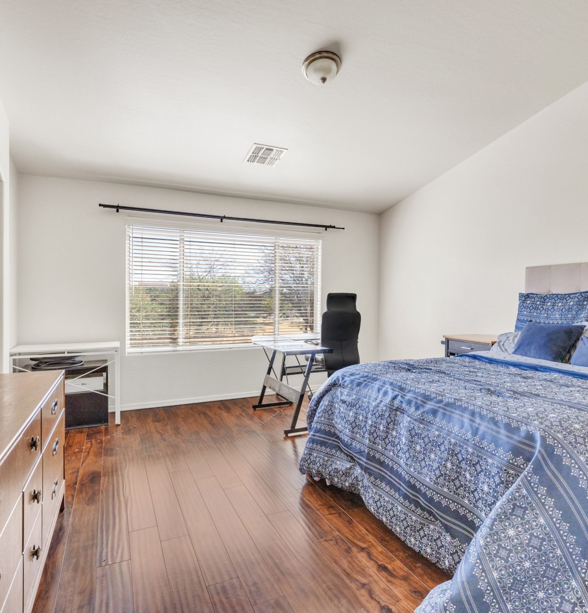 Interior of the primary bedroom at 845 S Cerise in Mesa, AZ, featuring rich dark wood flooring, a large window with views of the community park in the gated La Fortina community.