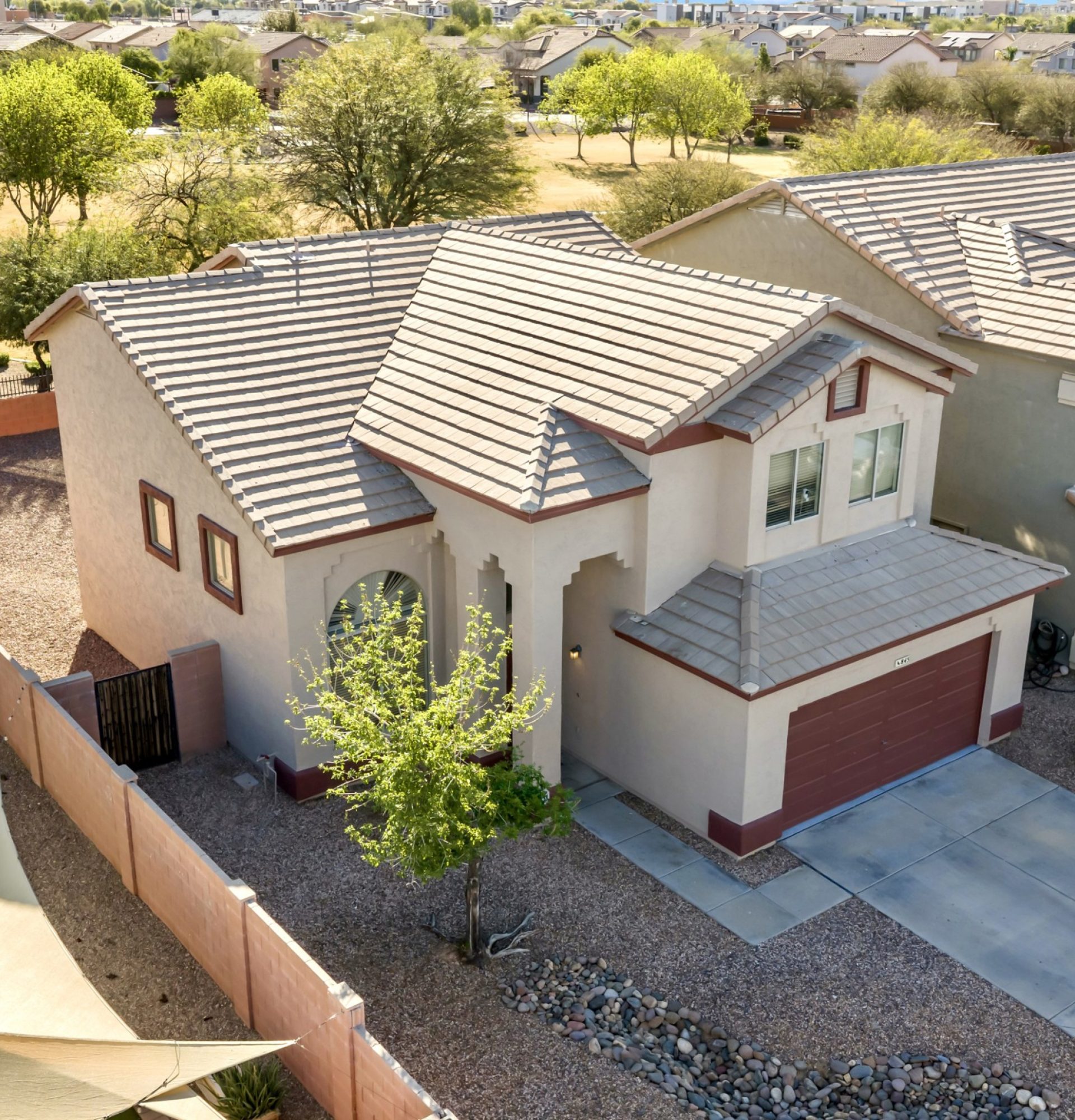 High-angle aerial view of the front and side of 845 S Cerise in Mesa, AZ, showcasing the modern two-story exterior, two-car garage, and its close proximity to the expansive green community park in the gated La Fortina neighborhood.