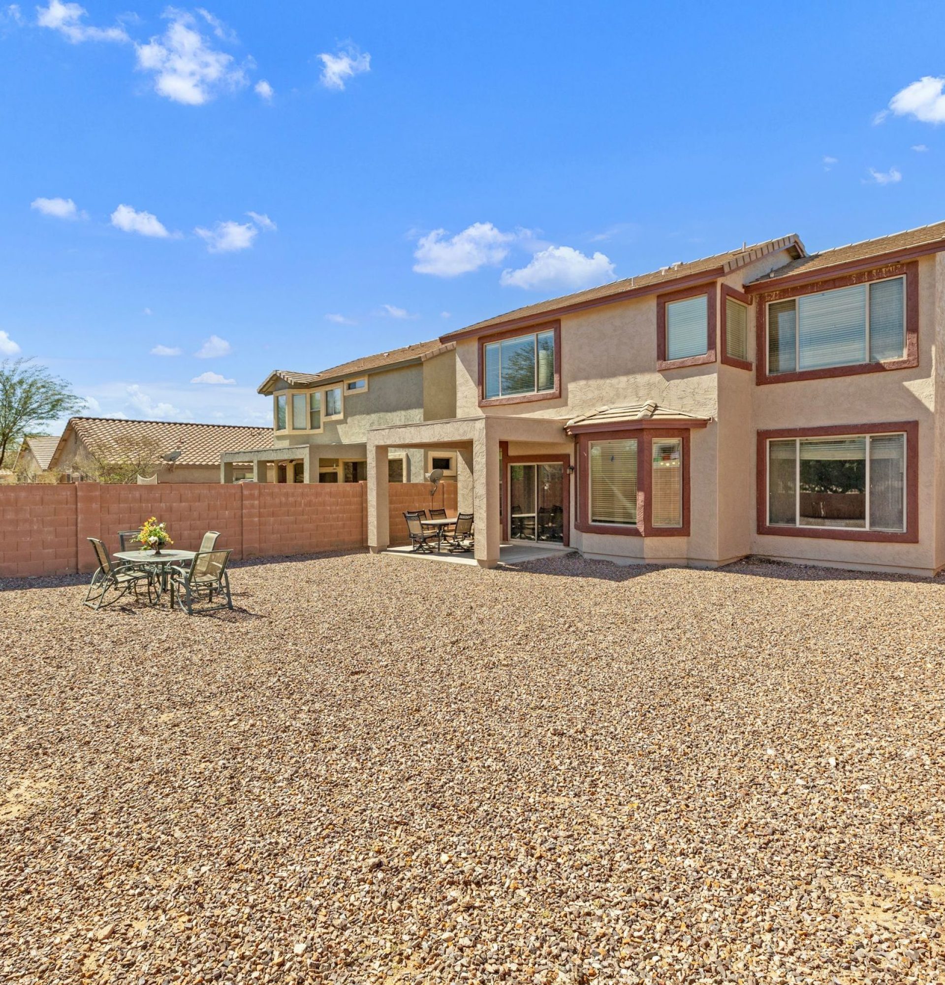 View of the huge oversized premium backyard at 845 S Cerise in Mesa, AZ, featuring low-maintenance desert landscaping, a covered patio, and a privacy wall, located in the gated La Fortina community near the neighborhood park and playground.