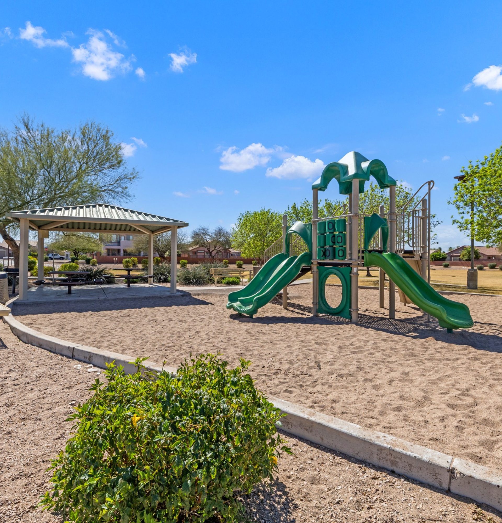 Aerial drone photography of 845 S Cerise in Mesa, AZ, showing the home’s backyard bordering a large, green HOA-maintained park with walking paths, mature trees, and a gazebo under a bright blue sky.
